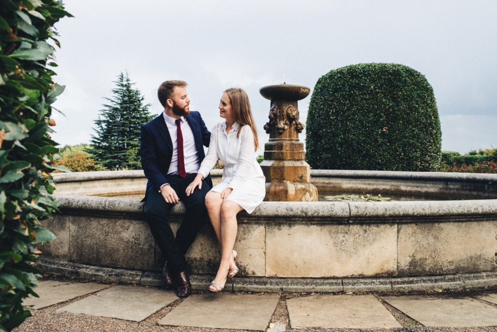 Elegant couple sitting on fountain in Alexandra Palace Gardens