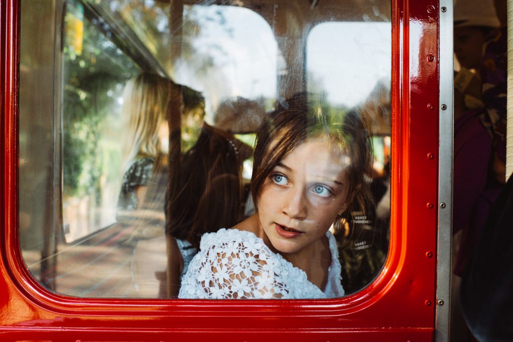 Misty, young girl in vintage red bus at wedding